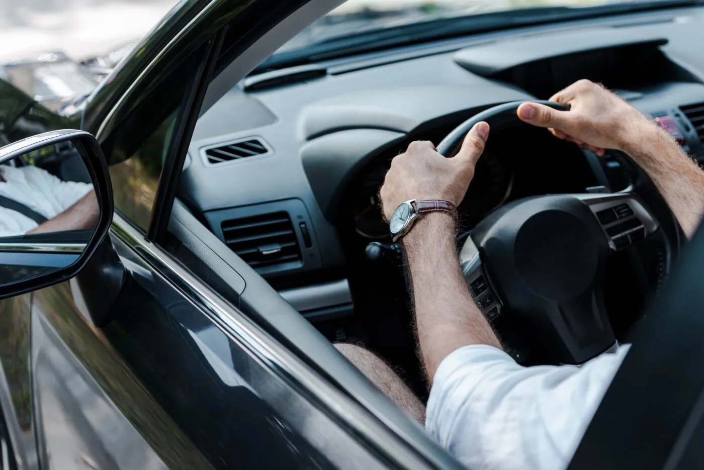 A driver's hands on the steering wheel of a car