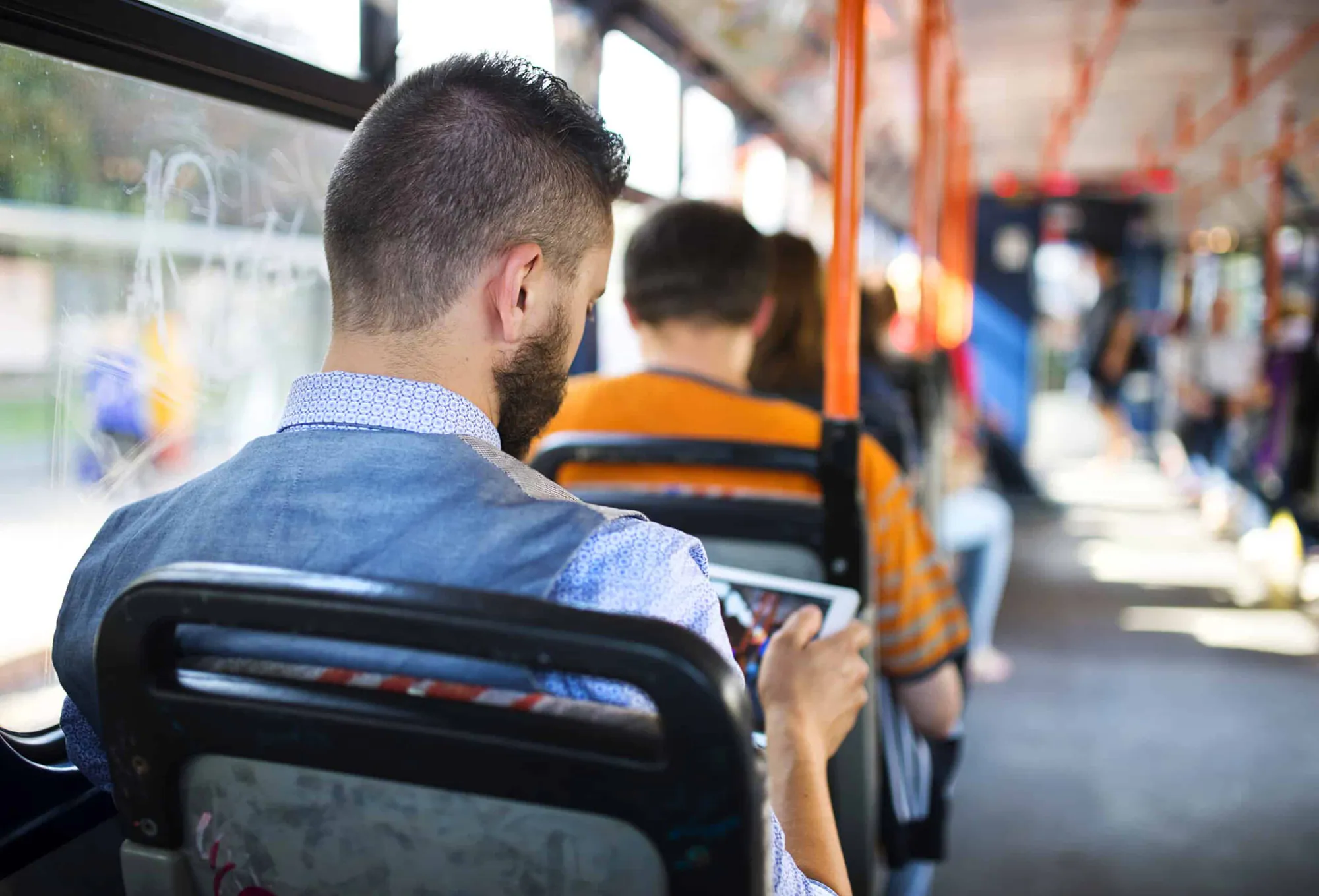 A passenger looks at a tablet while seated on a city tram