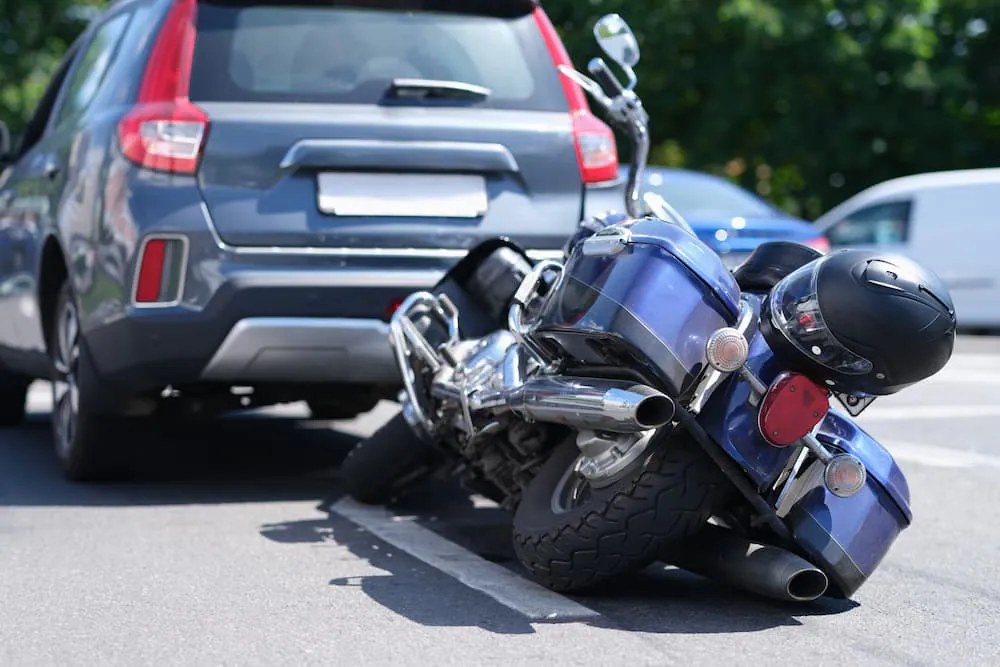 A motorcycle on its side behind an SUV after a crash, a helmet resting on the bike