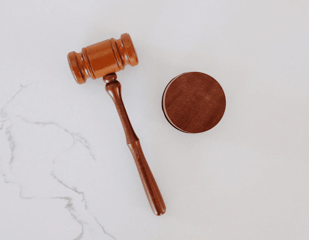 A wooden gavel and sound block on a white marble surface
