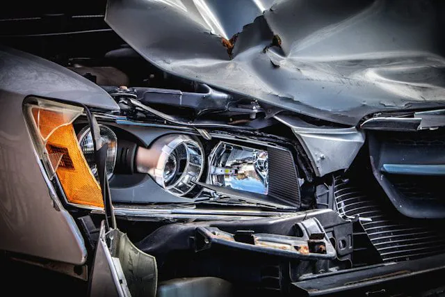The crumpled hood and broken headlight of a car after a collision