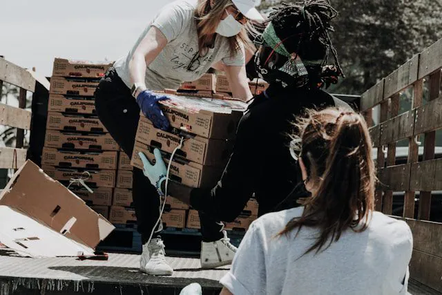 Volunteers in masks and gloves unloading boxes of food from a truck