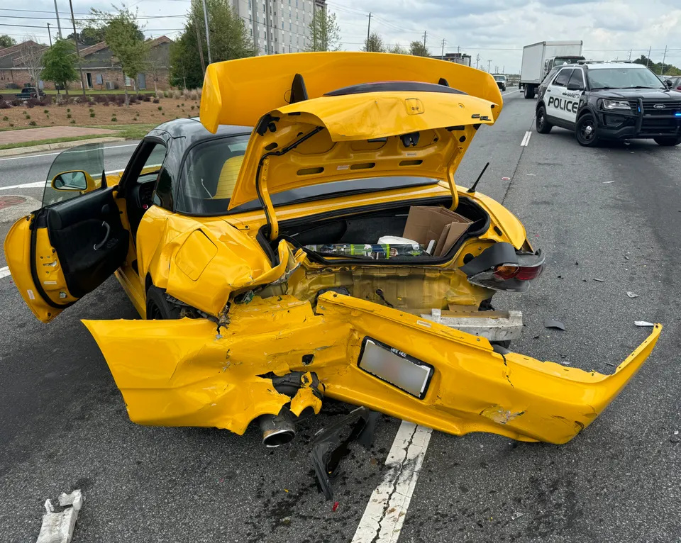 A rear-ended car after a collision, a police vehicle behind it