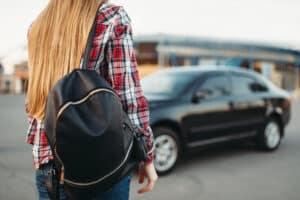 Young woman driver with bag against a car