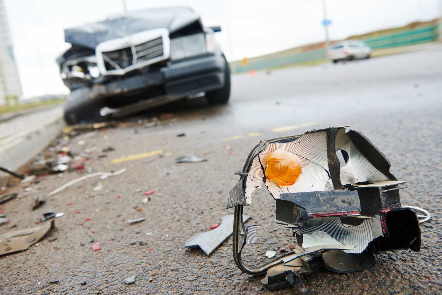 Close-up of vehicle debris from a hit-and-run accident, showing broken car parts.