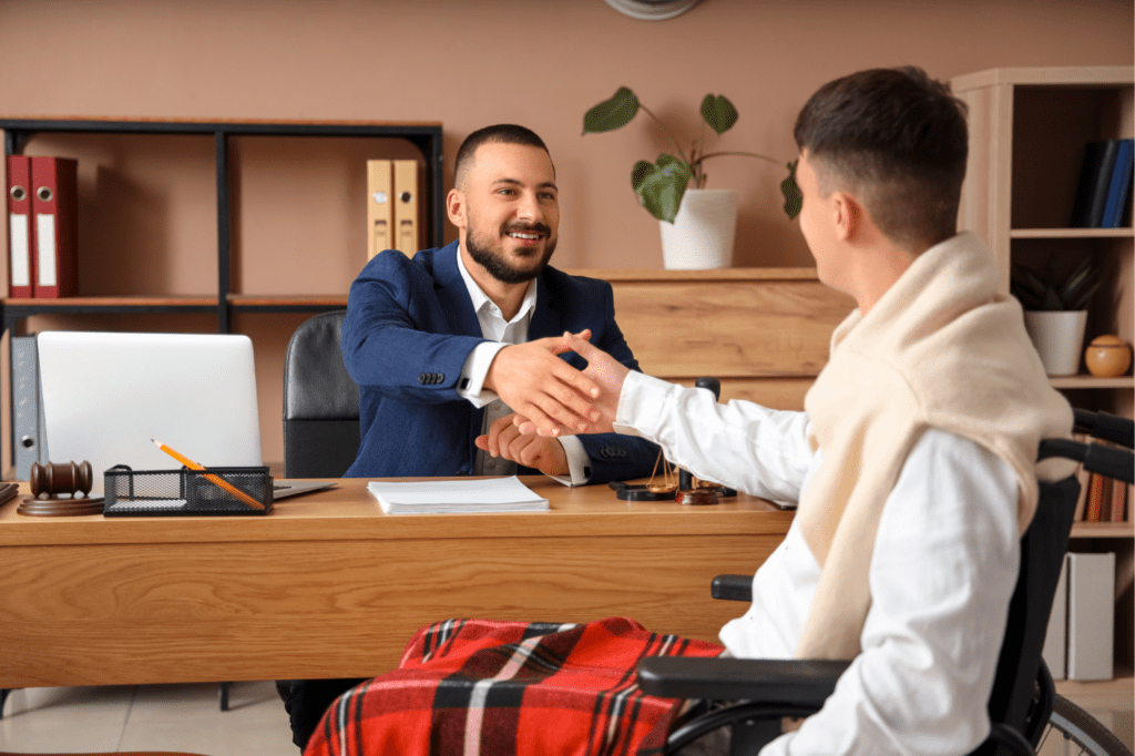Lawyer shaking hands with a recovering client in a wheelchair, symbolizing justice and support after a pedestrian accident.