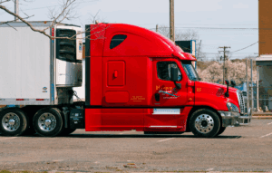 Red Semi-truck hauling a white cargo crate in Georgia.